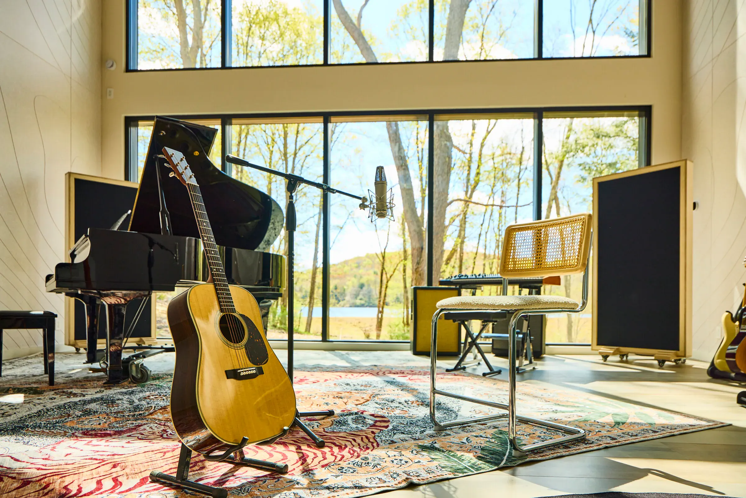 Martin acoustic guitar on stand in the Verdant Sound live room, grand piano and lake backdrop